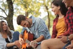 young adolescents playing guitar outside smiling