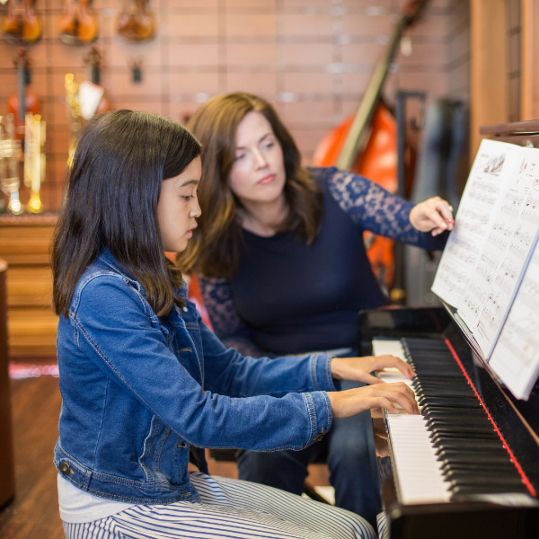 student playing the piano during a music lesson with a piano teacher