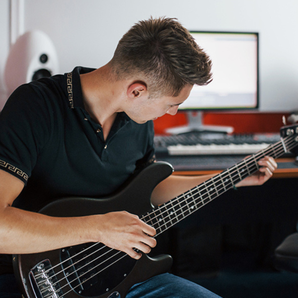 student playing the guitar during an online bass lesson