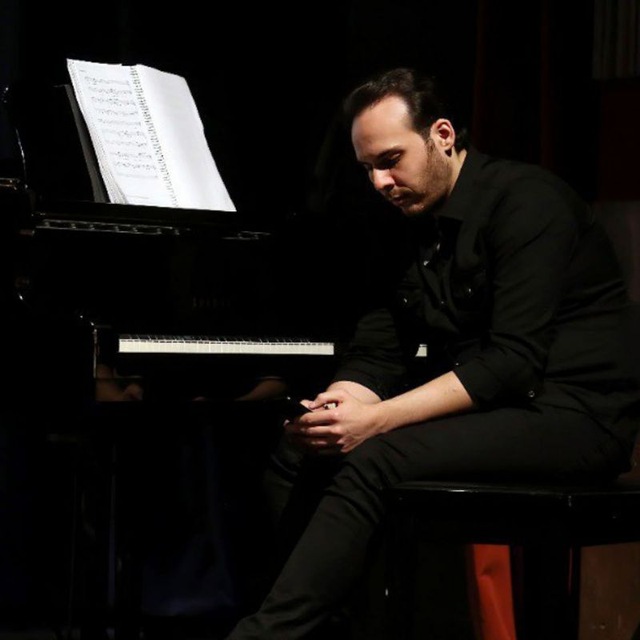 Pejman A., piano teacher in Toronto, seated beside a piano
