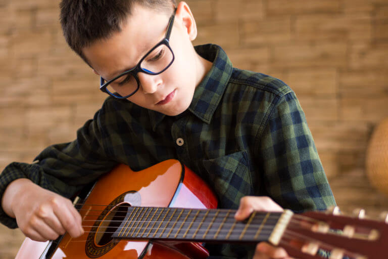 A music student practices guitar at home in Toronto hoping to make his teacher proud